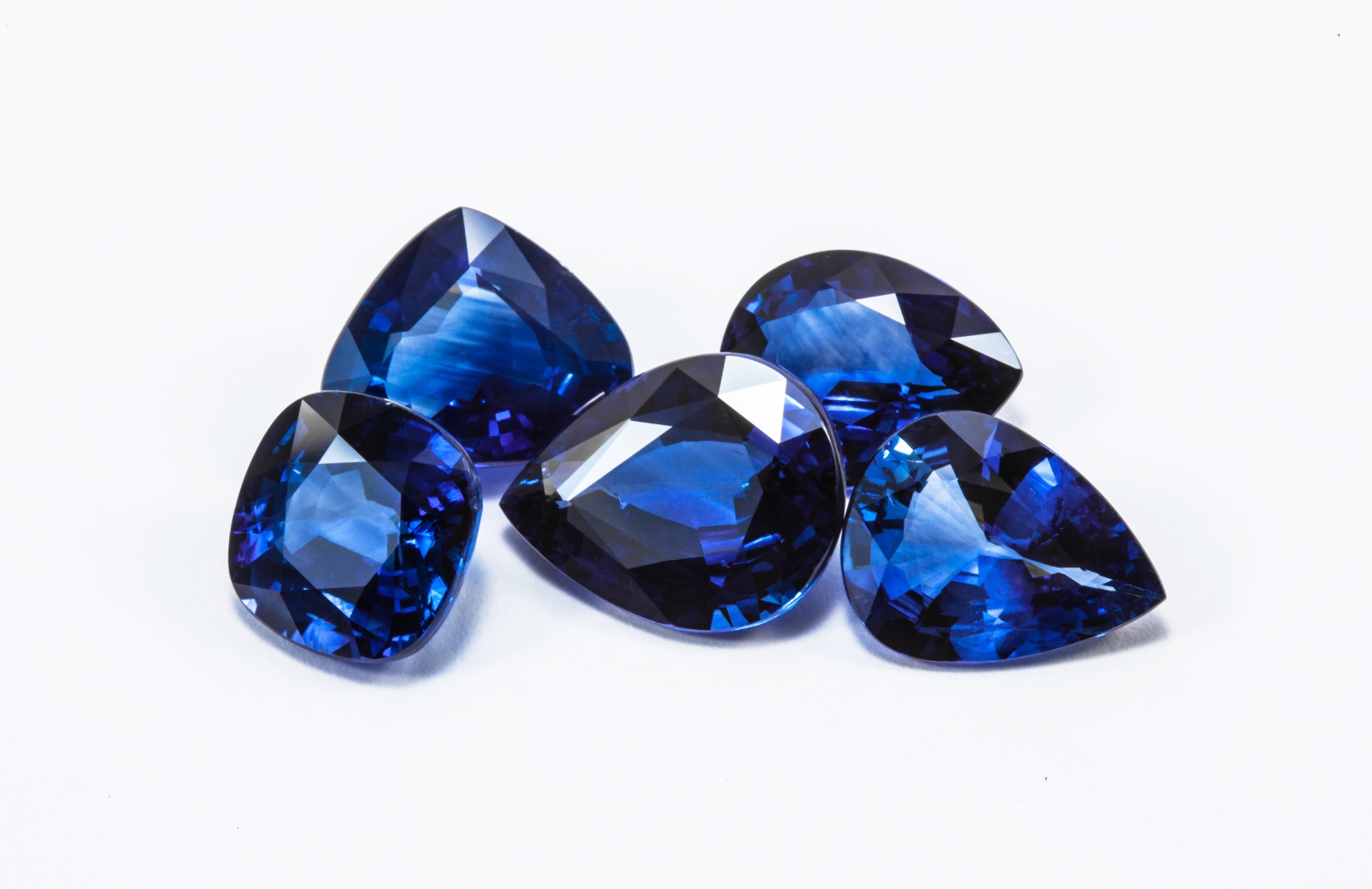 varias gemas de zafiro piedra de nacimiento de septiembre sobre un fondo blanco. Las gemas tienen diferentes cortes con azules profundos y tallados perfectos